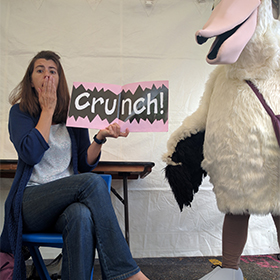 A woman looks surprised next to a giant pelican