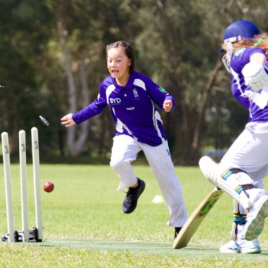 Cricket stumps that have been hit by a ball with a player running to catch