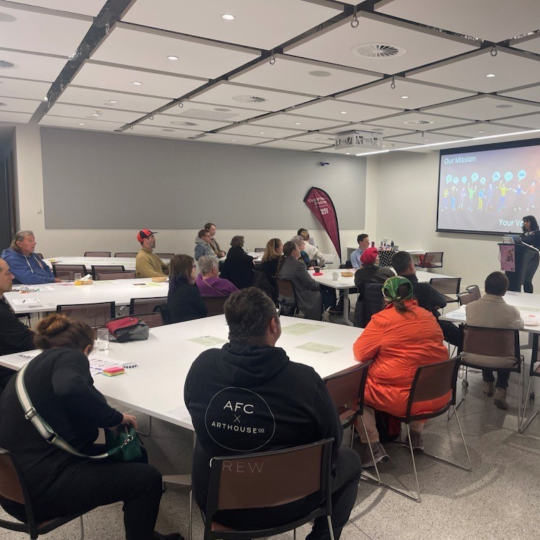 People sitting at tables watching a workshop presentation