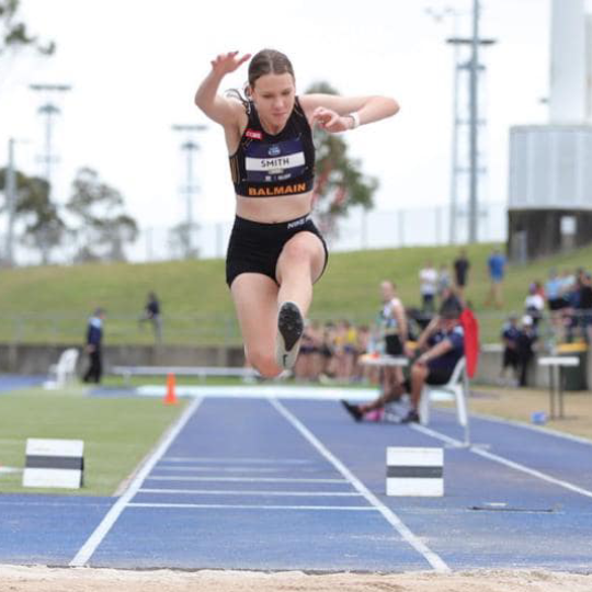 Female long jumping into sand