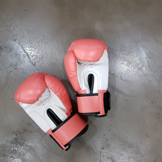 Red and white boxing gloves on a concrete surface