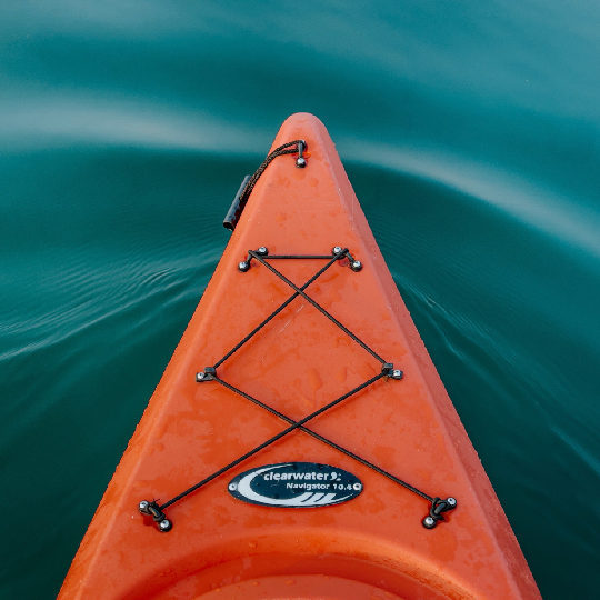Front end of an orange kayak moving through water