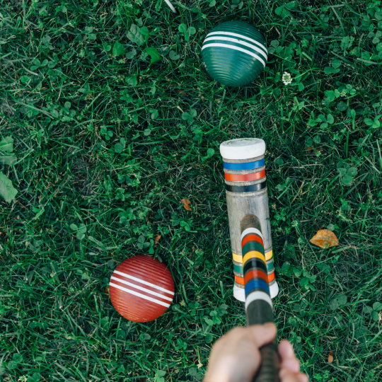  Croquet club held in front of a green ball ready to hit and a red ball to the left of the club