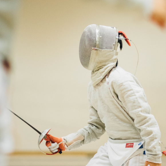 Person dressed in protective attire holding a fencing sword 