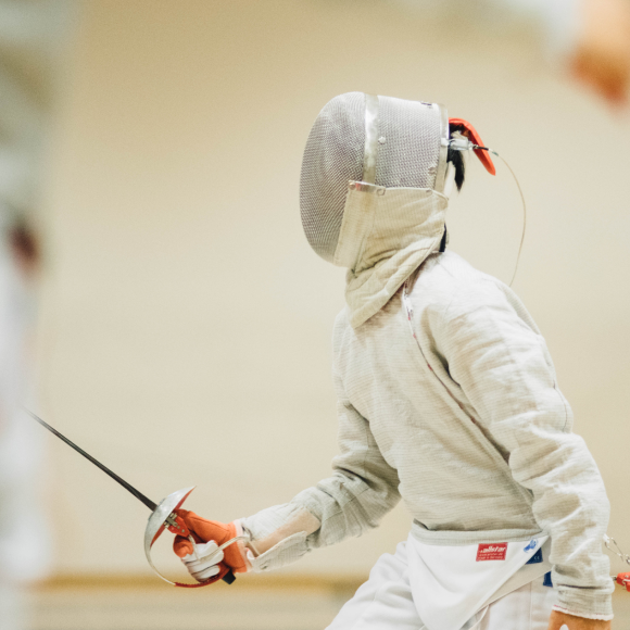  Person dressed in protective attire holding a fencing sword 