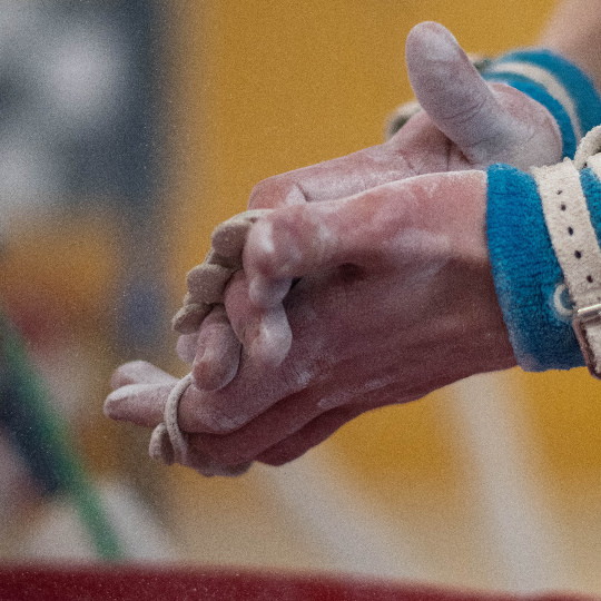 Hands rubbing together covered in chalk wearing blue and white wrist braces