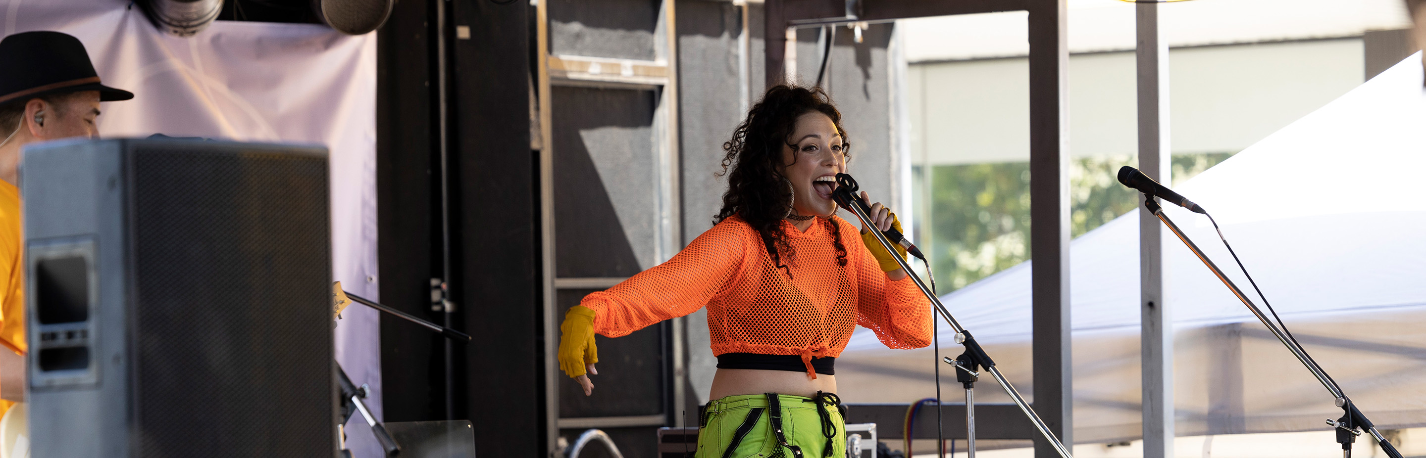 a lady in yellow sings into a microphone