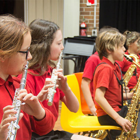 Group of young musicians playing various musical instruments sitting on yellow chairs