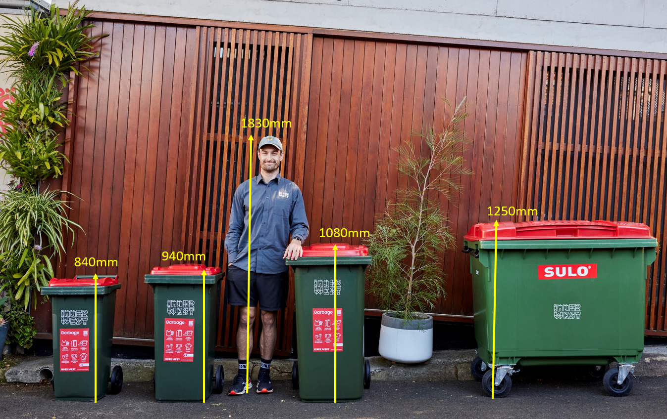 man stands beside 4 bins to show height comparitives