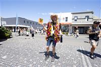 A Marrickville streetscape featuring a young bearded person wearing a tassled hi vis vest holding up a festival program