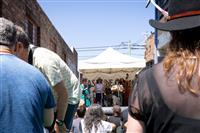 A framed shot looking past peoples shoulders at a six piece band playing underneath a white marquee in a laneway