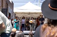 A tightly framed shot looking past peoples shoulders at a six piece band playing underneath a white marquee in a laneway