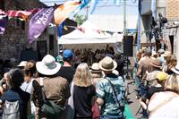 A high shot of a six piece band playing to a crowd of people in a laneway with colourful bunting above