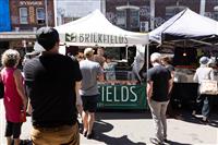 Streetscape with stalls, highlighting one with green branding 