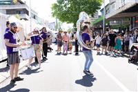 A Marrickville streetscape featuring a brass band wearing purple shirts with branding 