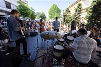 A back of stage shot of a band including a drummer, guitarist and vocalist playing to a large audience