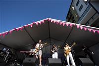 A front of stage shot looking up at three guitarists and one keyboardist, plus an auslan interpreter