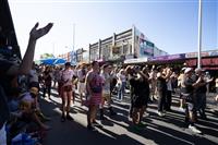 A crowd of people gathered on a streetscape cheering a stage performance behind the photographer