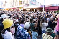 A densely packed crowd enjoying a stage performance off camera, gathered on a Marrickville street