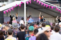 A close cropped image taken mid crowd featuring three performers on a pink fringed stage, plus a DJ and auslan interpreter