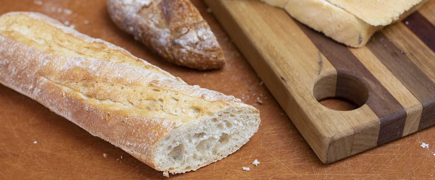 Slices of different types of bread on and around a wooden chopping board