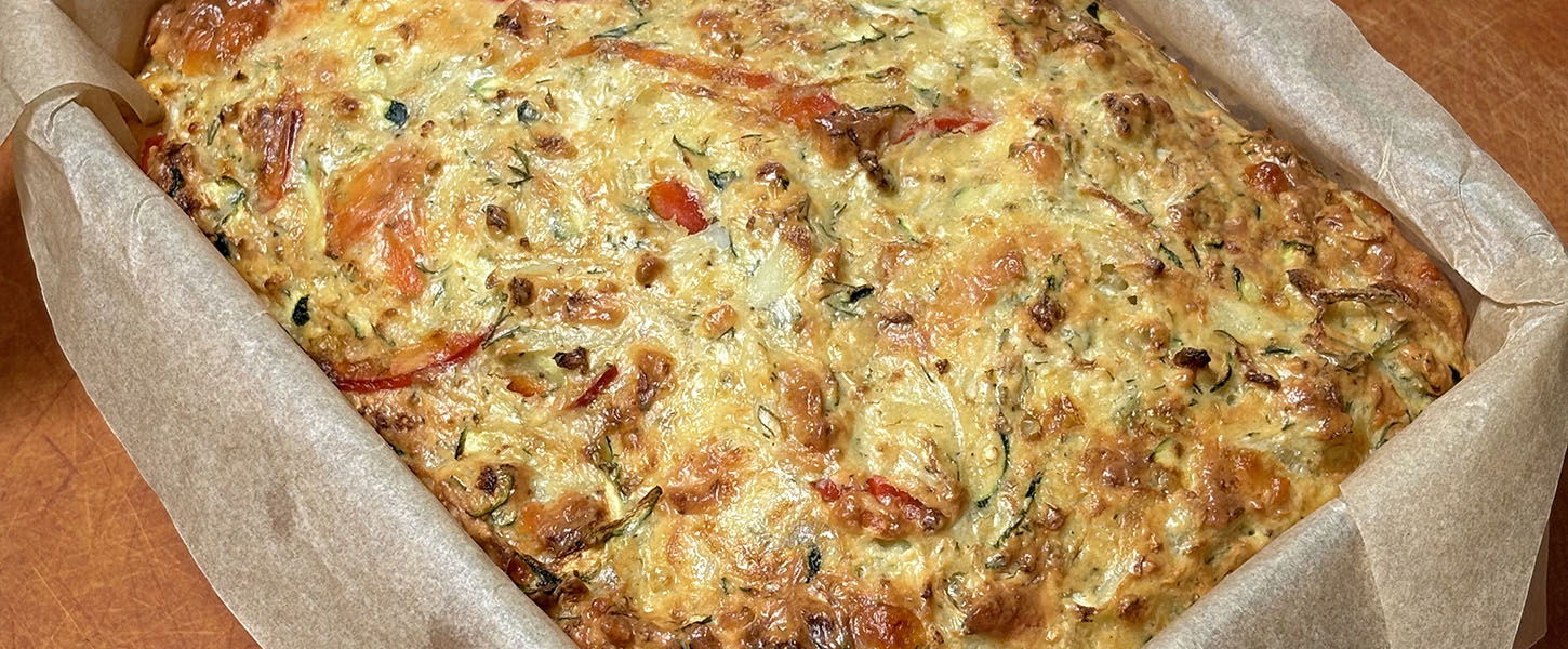 A whole egg and vegetable baked slice sitting in a deep oven tray