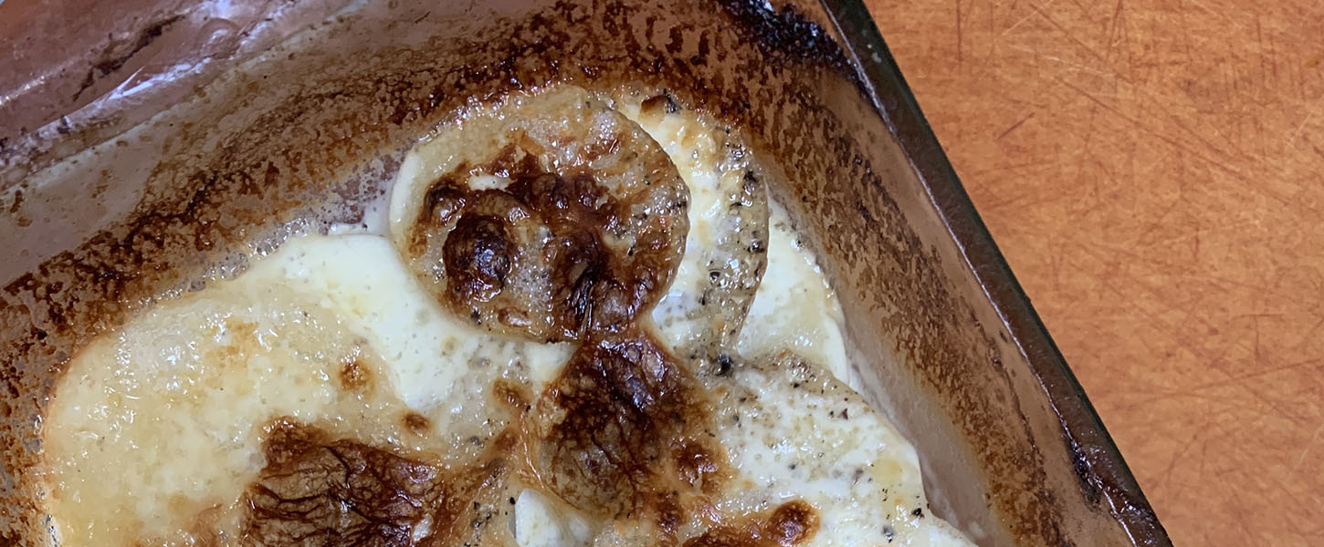 A whole cooked potato bake in a glass oven tray