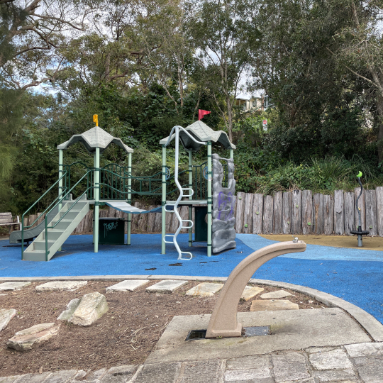 Play equipment and a water bubbler in an urban playground setting.
