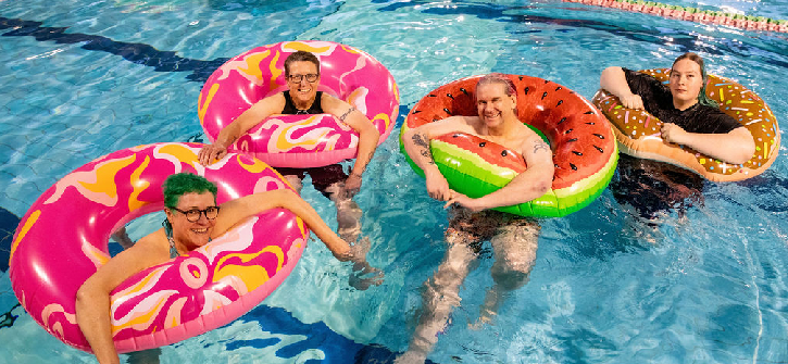 Four people in colourful floation rings in a pool