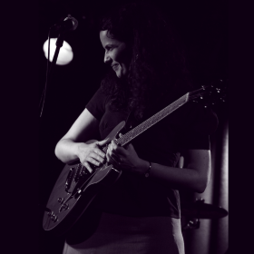 black and white photo of Cassandra with guitar