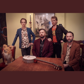 band poses at table with stuffed fox 
