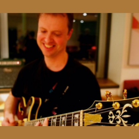 person smiles holding guitar 