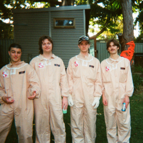 analogue photo of four people in cream jumpsuits in a garden