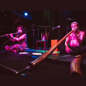 Yulugi duo seated on stage floor with flute and didgeridoo