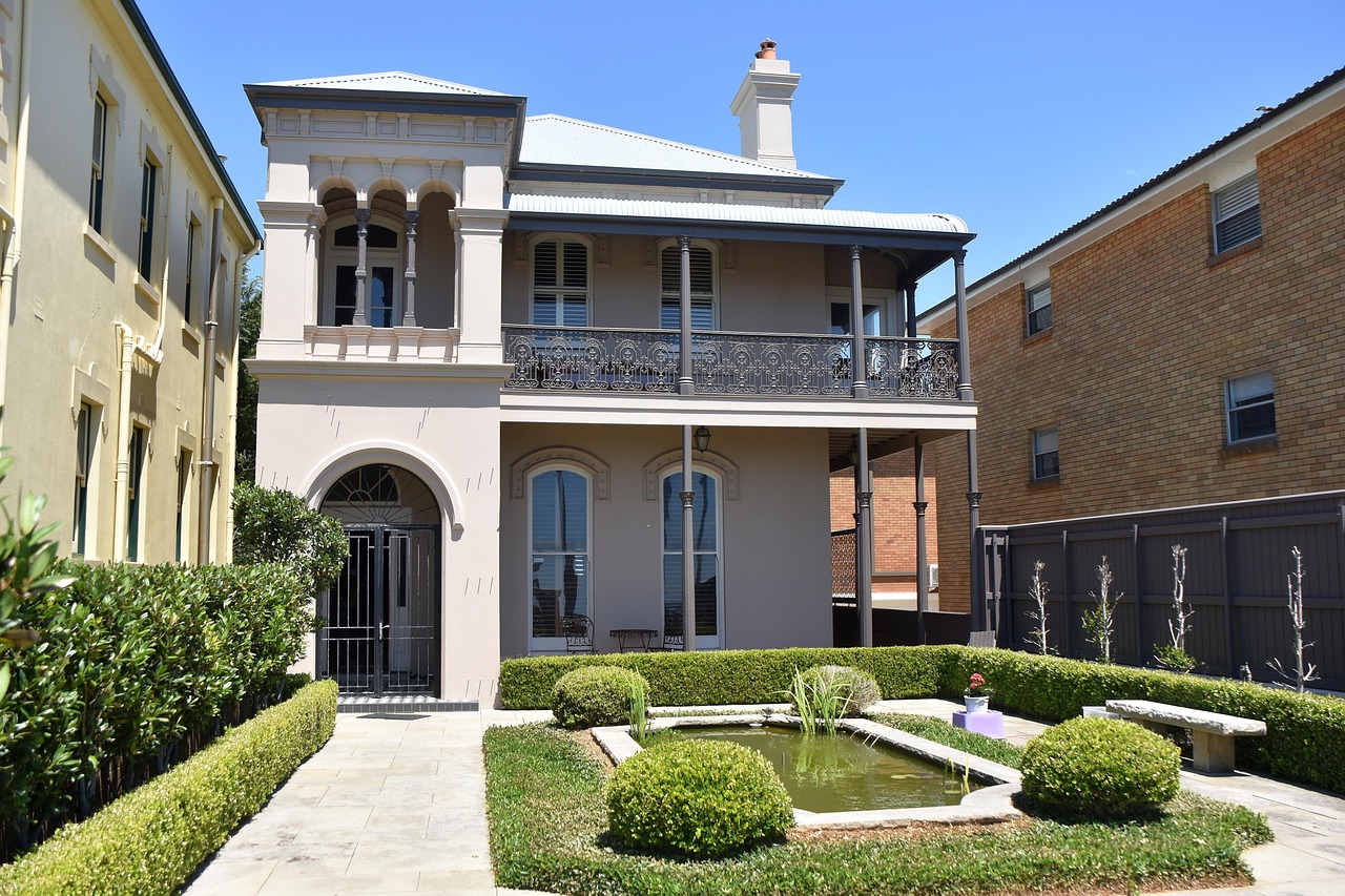 image of two story boarding house with a garden and pond at the front