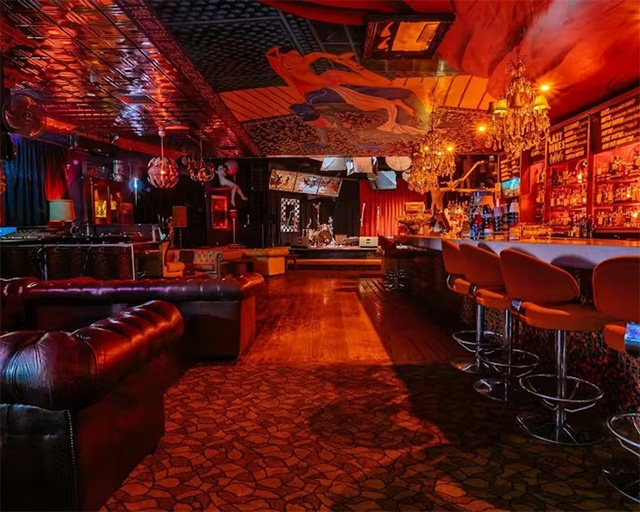 The interior of a heavily-decorated live music venue, lit in dim warm red tones.