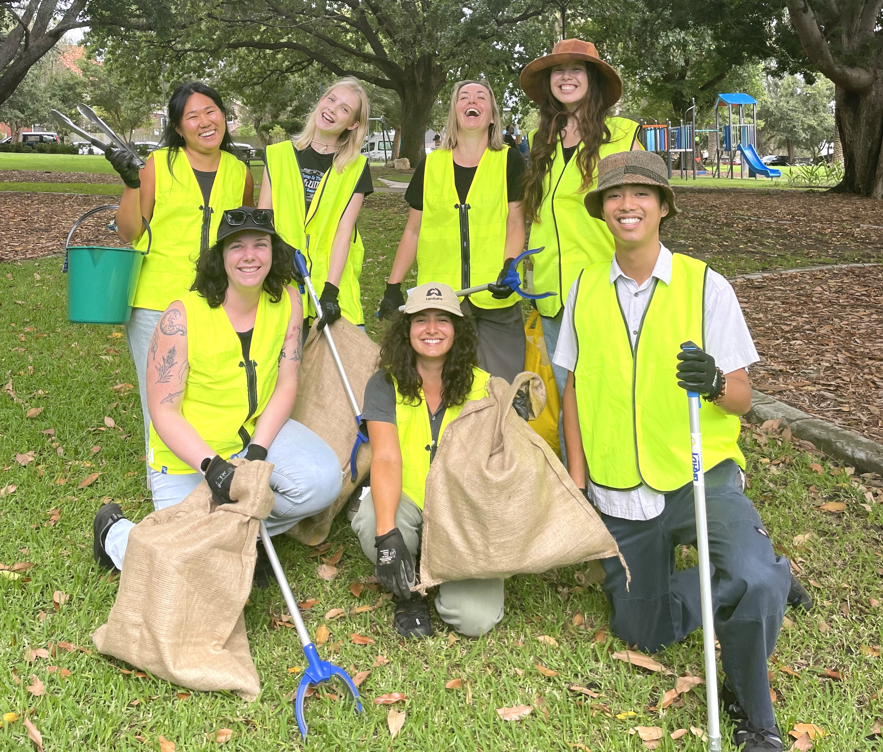 an image of a group of staff in yellow hi-vest and gloves outdoor smiling