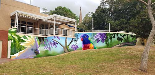 A photo of a painting of birds along the bottom of the Summer Hill Community Centre featuring a cockatoo and a rainbow lorakeet.